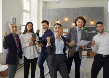Happy triumphant business team celebrating giving successful presentation in work meeting